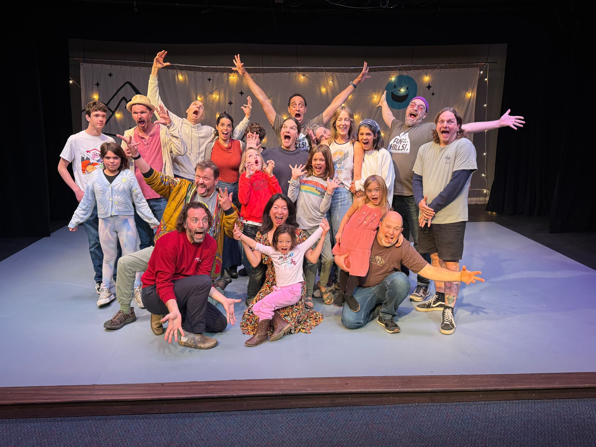 Youth workshop cast mugging for a group photo on stage