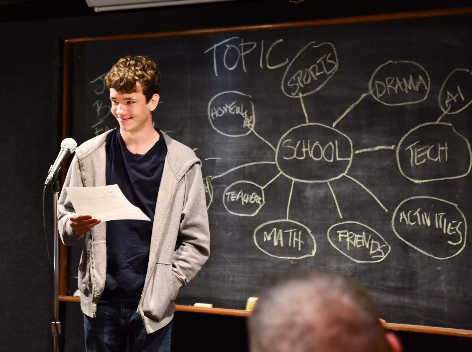 Teen reading his jokes at the youth workshop showcase